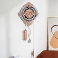 Horloge murale accrochée à un mur clair, contrepoids et balancier en forme de note déployés