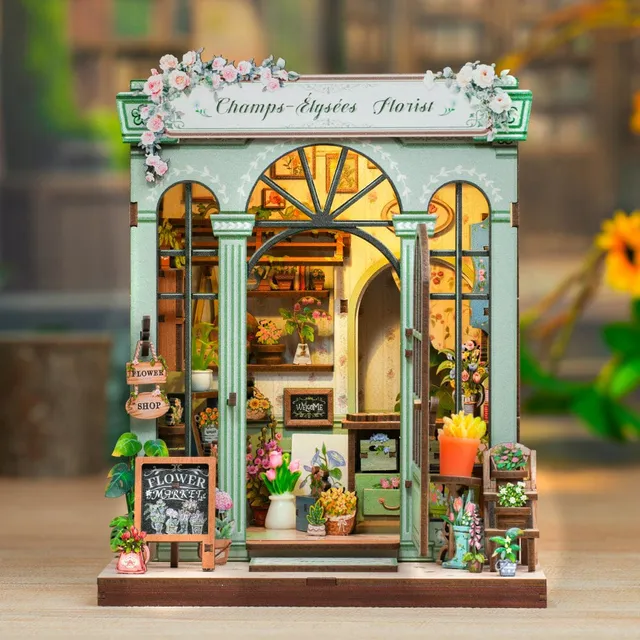 Boutique Champs-Élysées Florist montée, façade vert d’eau et bouquets, éclairée de l’intérieur