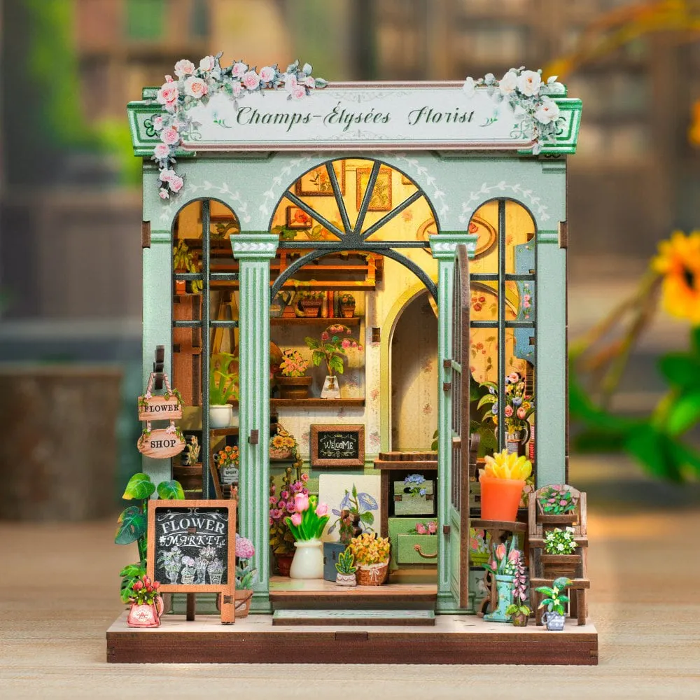 Boutique Champs-Élysées Florist montée, façade vert d’eau et bouquets, éclairée de l’intérieur