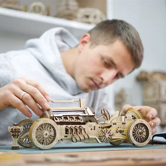 Un homme assemble la voiture de course en bois sur son établi