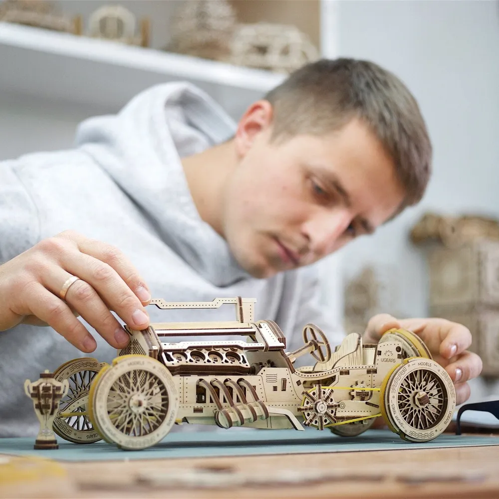 Un homme assemble la voiture de course en bois sur son établi