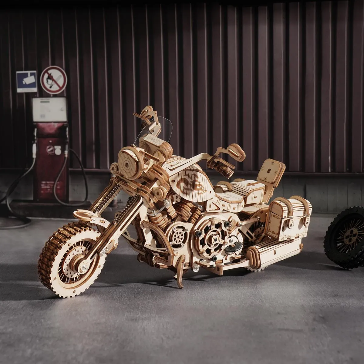 La moto dans un garage aux murs de tôle, à côté d'une vieille pompe à essence