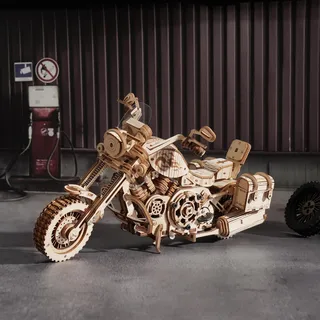 La moto dans un garage aux murs de tôle, à côté d'une vieille pompe à essence