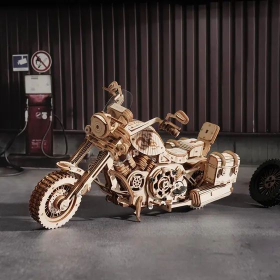 La moto dans un garage aux murs de tôle, à côté d'une vieille pompe à essence