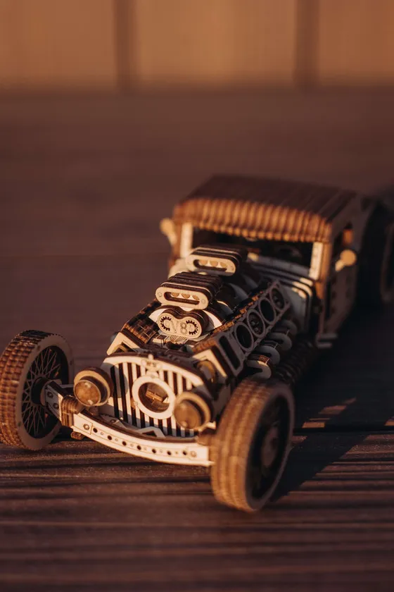 Le hot rod en bois posé sur une table en bois sombre, calandre et V8 au premier plan