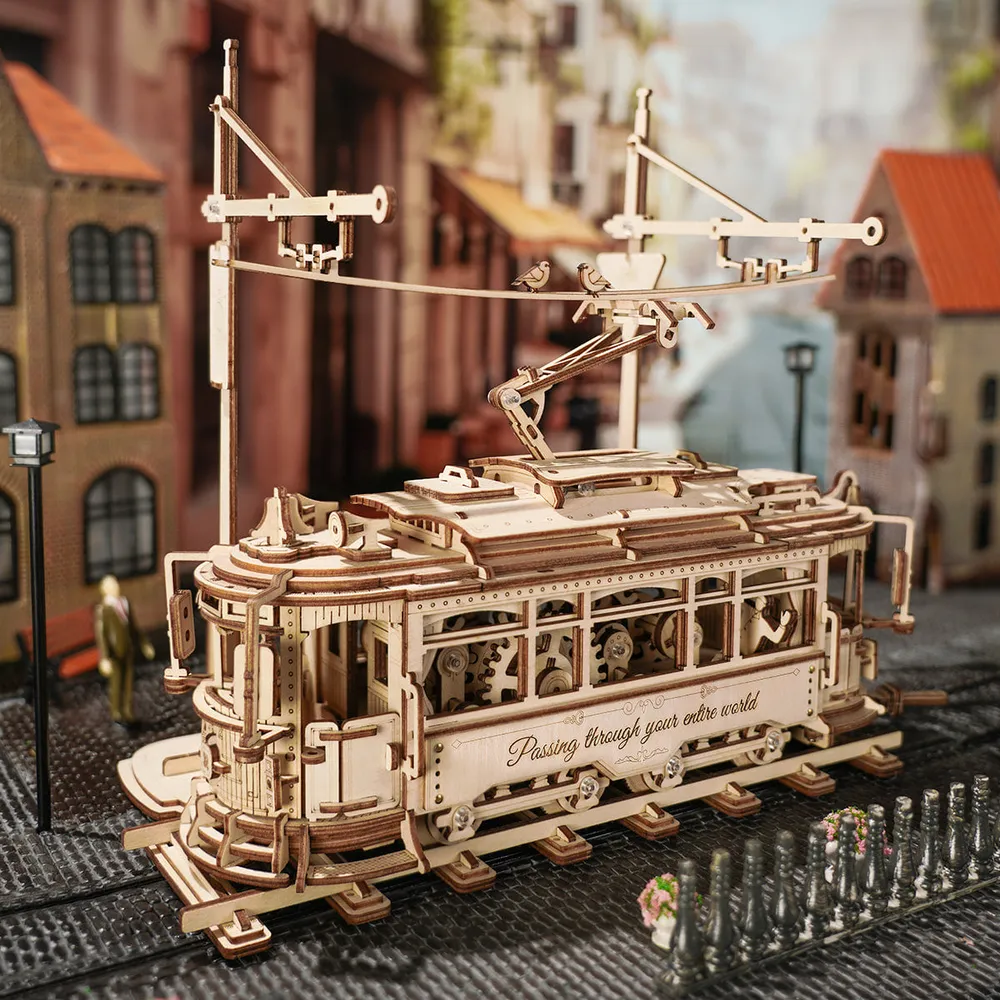 Tramway en bois circulant dans une rue miniature bordée d'immeubles et d'un réverbère