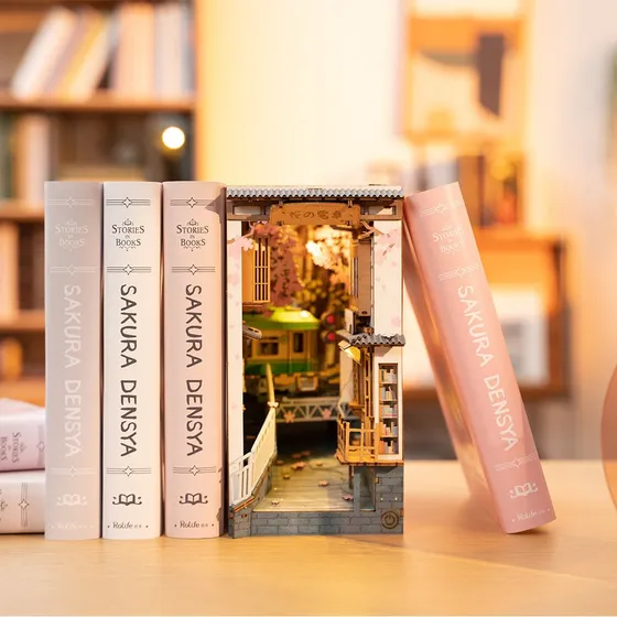 Le Sakura Densya glissé entre des livres roses et blancs sur une étagère