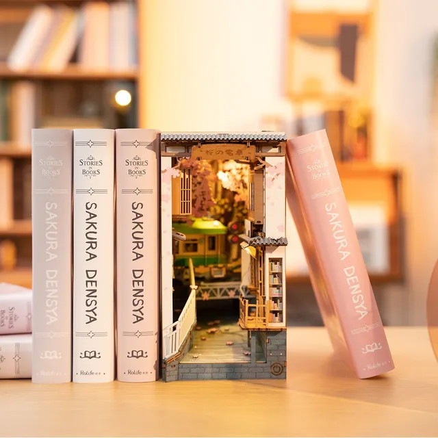 Le Sakura Densya glissé entre des livres roses et blancs sur une étagère