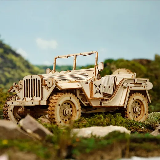 La jeep en bois posée parmi les rochers et la végétation, devant un ciel de montagne