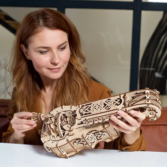 Femme souriante tenant à deux mains l'instrument de bois terminé dans un salon