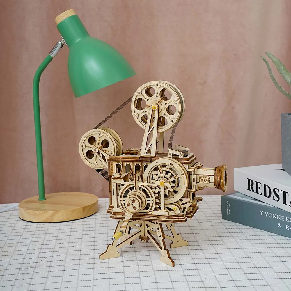 Le projecteur sur un bureau à côté d’une lampe verte et de livres