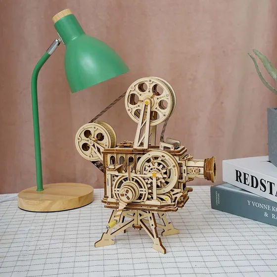 Le projecteur sur un bureau à côté d’une lampe verte et de livres