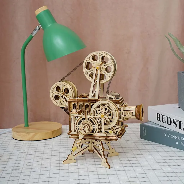 Le projecteur sur un bureau à côté d’une lampe verte et de livres