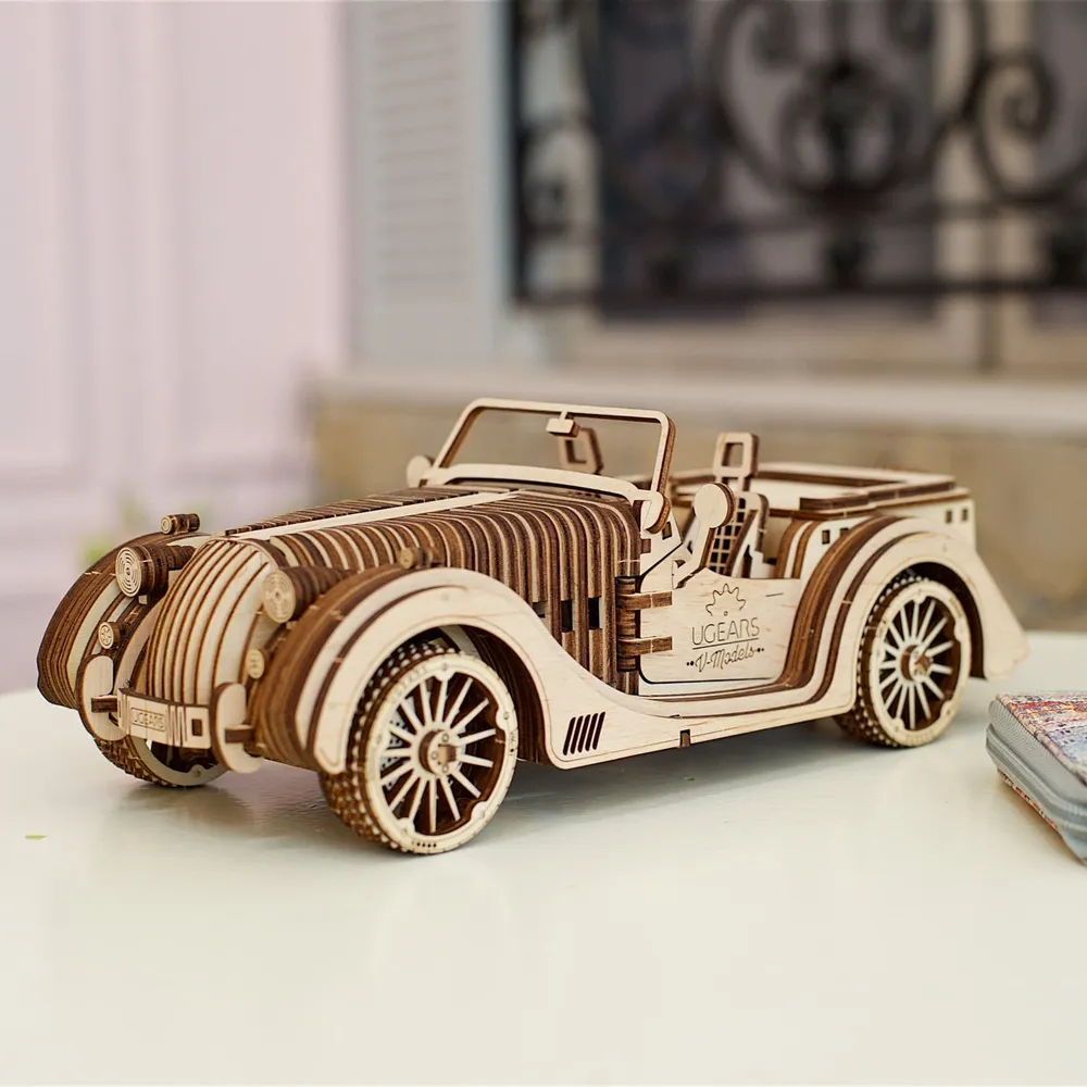 Cabriolet en bois sur une table blanche devant une fenêtre à ferronnerie floutée