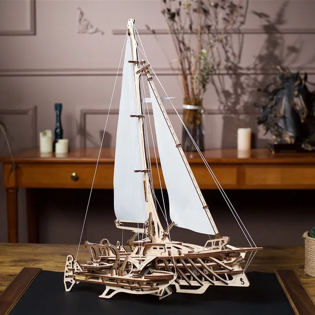Le trimaran en bois posé sur un bureau sombre, devant une console garnie de bougies