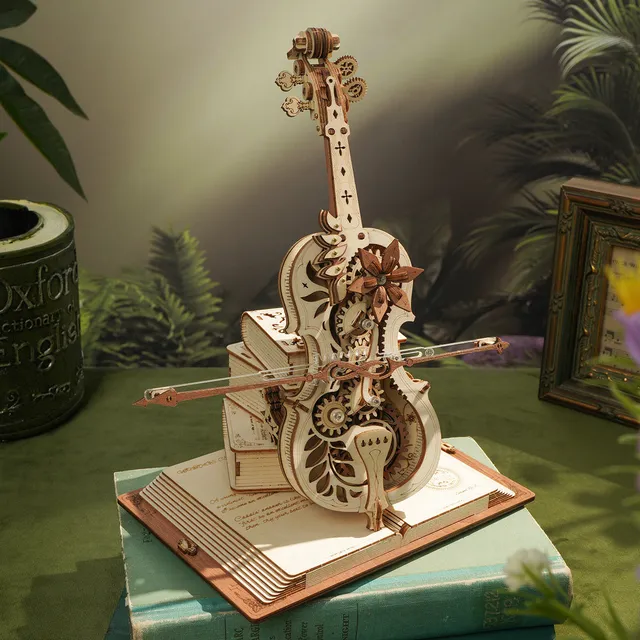 Violoncelle de bois posé sur un bureau vert entre un cadre ancien et des plantes