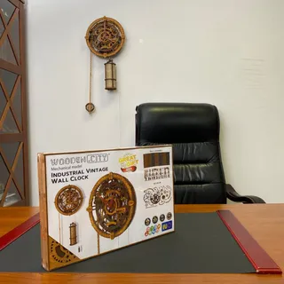L’horloge accrochée au mur d’un bureau, au-dessus d’un fauteuil en cuir, sa boîte posée sur le bureau