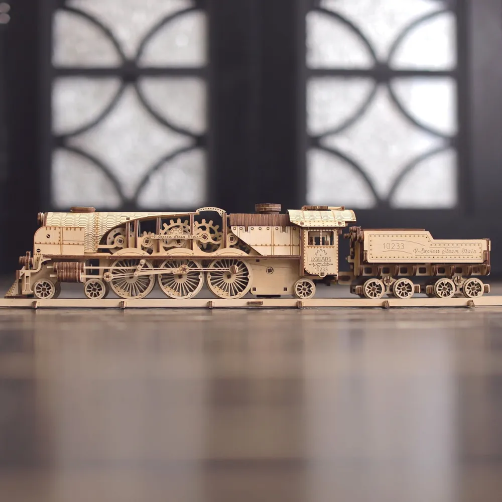Locomotive et tender de profil sur un sol brillant devant une grande fenêtre floutée