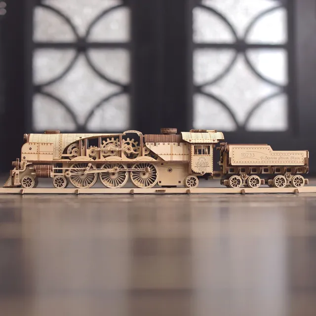 Locomotive et tender de profil sur un sol brillant devant une grande fenêtre floutée