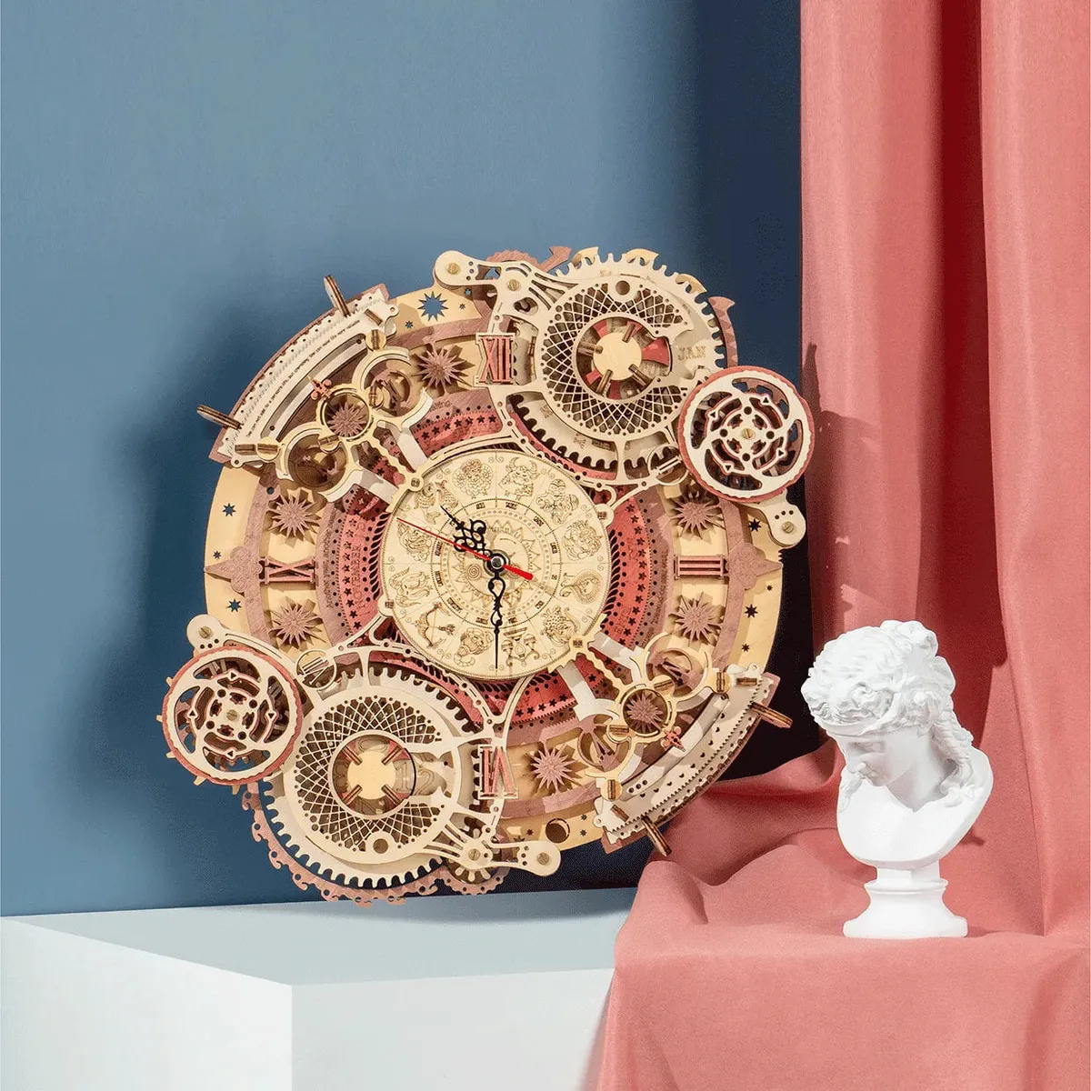 Horloge ronde accrochée à un mur bleu, rideau rose drapé et buste en plâtre à côté
