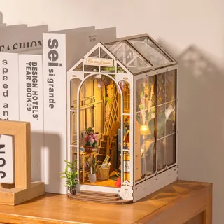 La serre miniature glissée entre des livres blancs sur une étagère en bois