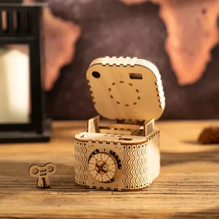 La boîte ouverte sur une table en bois, couvercle relevé, clé posée à côté, lanterne en arrière-plan