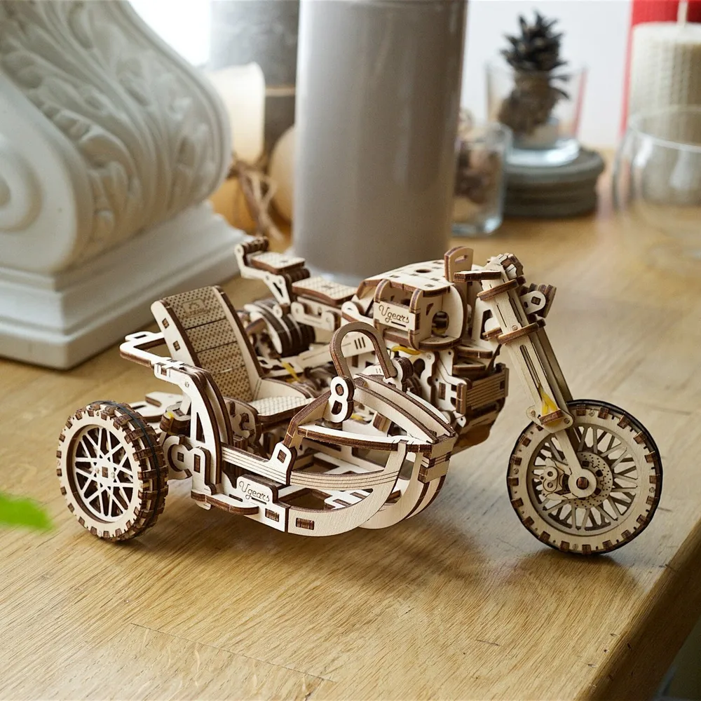 La moto à side-car en bois posée sur une table, dans un intérieur