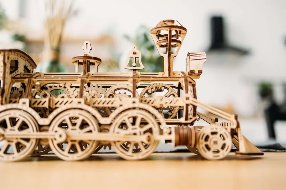La locomotive de profil : roues motrices, bielles, chaudière, cloche et cheminée évasée