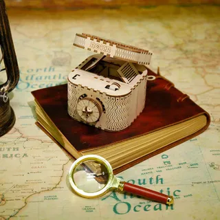 Le coffret entrouvert posé sur un carnet en cuir et une carte ancienne, à côté d'une loupe