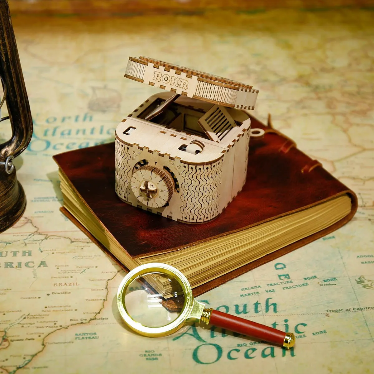 Le coffret entrouvert posé sur un carnet en cuir et une carte ancienne, à côté d'une loupe