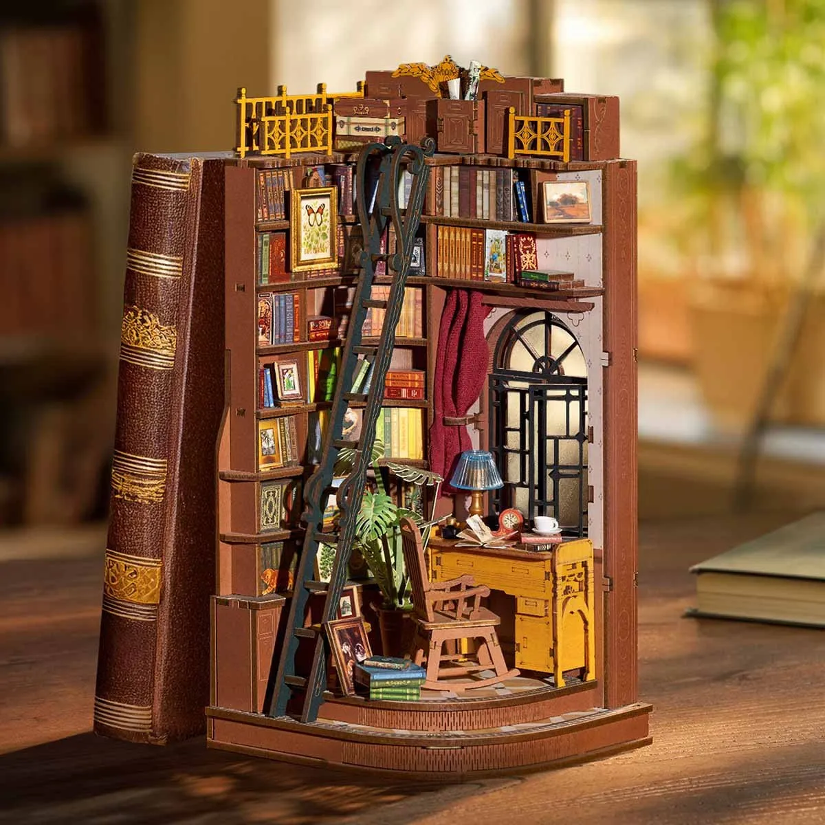 Le book nook à côté d’un grand livre relié, sur un bureau