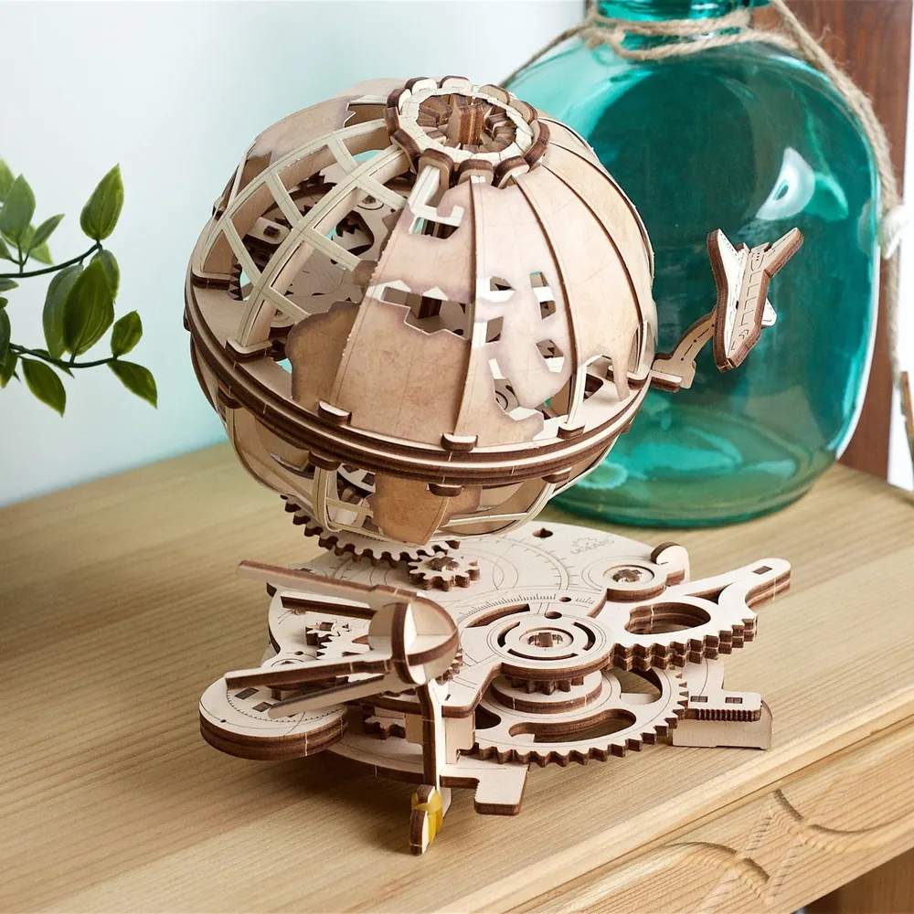Le globe en bois sur une étagère, devant une bouteille de verre turquoise et une plante