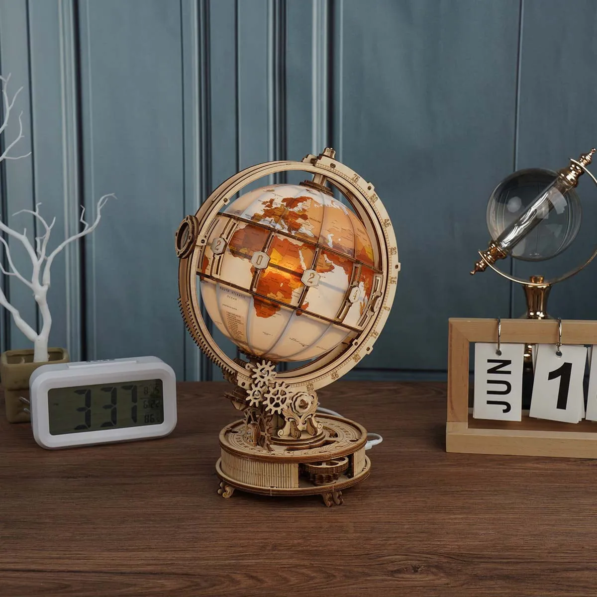 Le globe allumé sur un bureau en bois, entre un réveil et un calendrier à feuillets