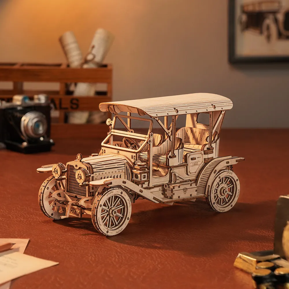 Voiture ancienne en bois sur un bureau de cuir brun, près d'un appareil photo à soufflet