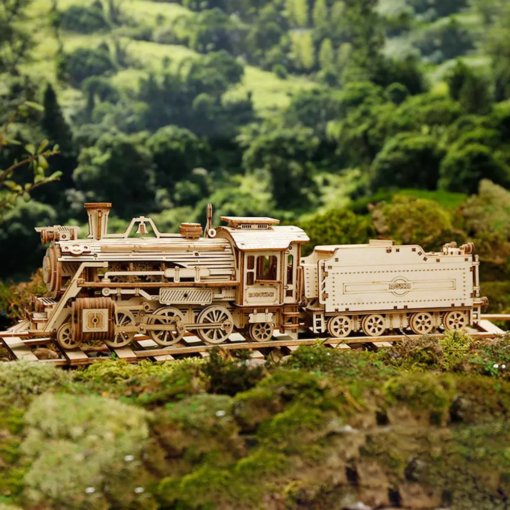 Locomotive en bois de profil sur ses rails devant des collines verdoyantes floutées