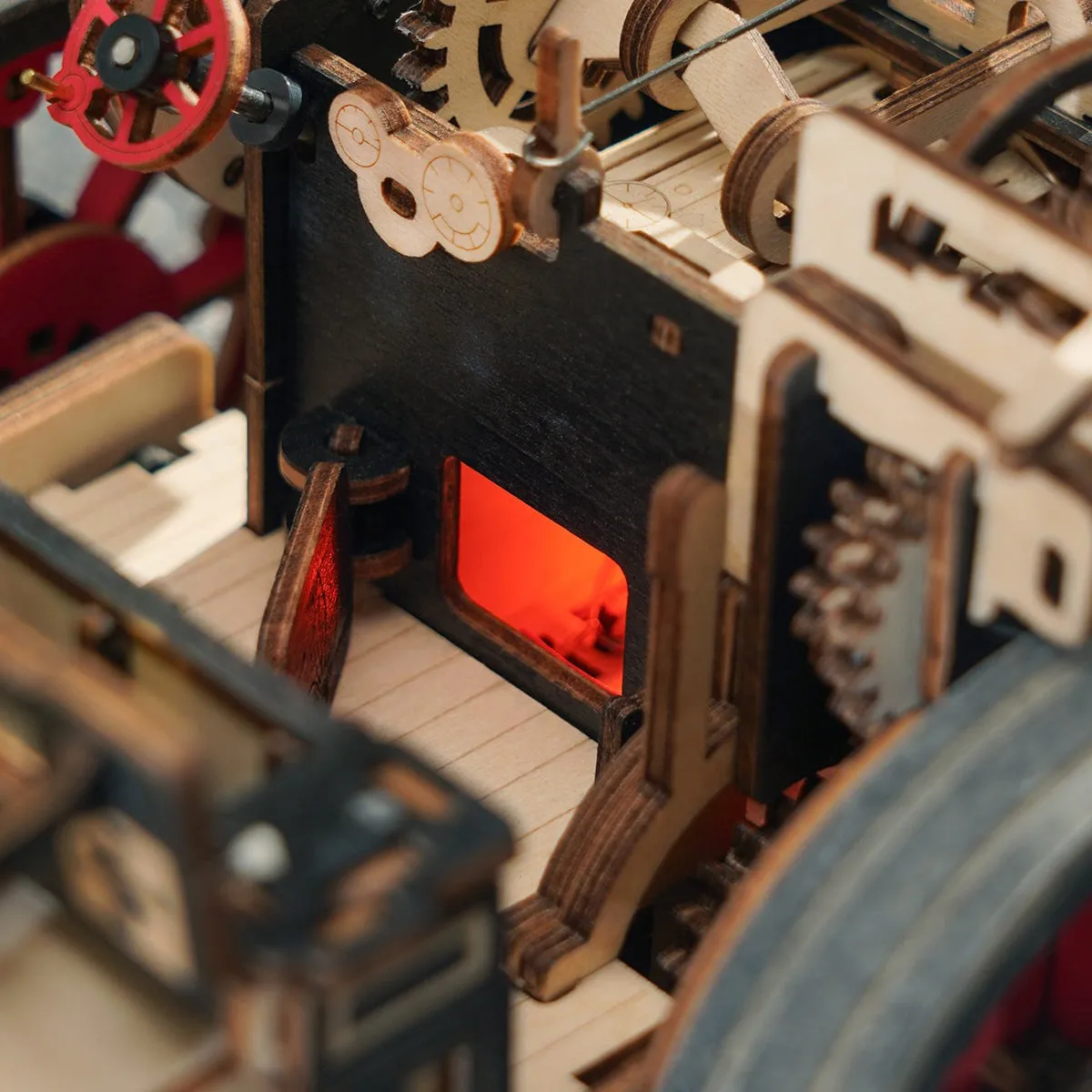 Le foyer éclairé en rouge à l'intérieur de la machine, entouré d'engrenages en bois