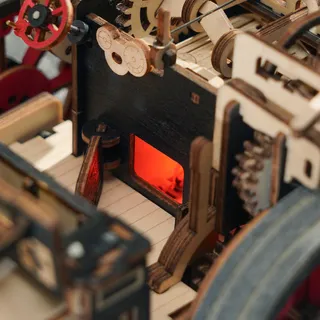 Le foyer éclairé en rouge à l'intérieur de la machine, entouré d'engrenages en bois