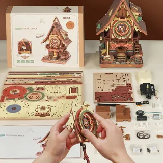 Boîte, planches colorées prédécoupées, notice et composants étalés sur une table, deux mains au centre