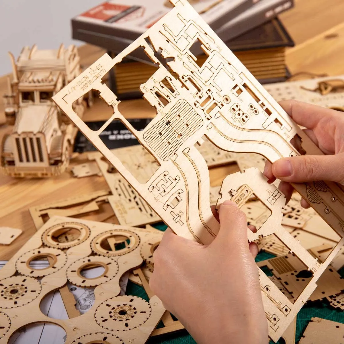Mains détachant une pièce d’une planche de bois, pièces du kit sur la table