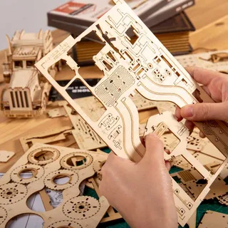 Mains détachant une pièce d’une planche de bois, pièces du kit sur la table