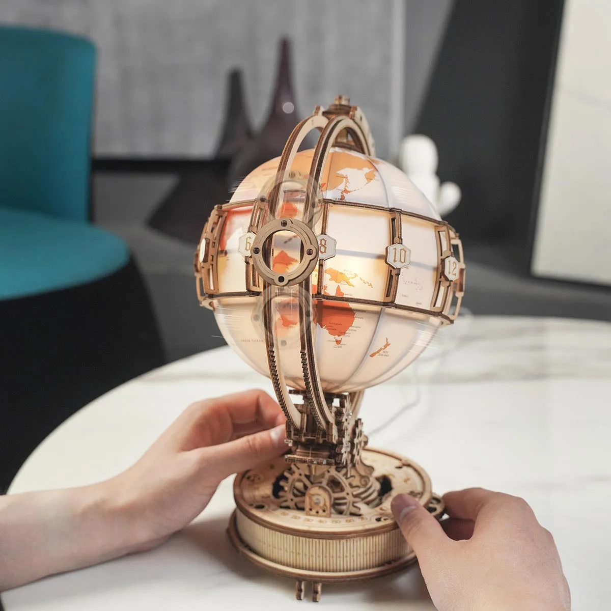 Deux mains font pivoter le globe allumé posé sur une table en marbre blanc
