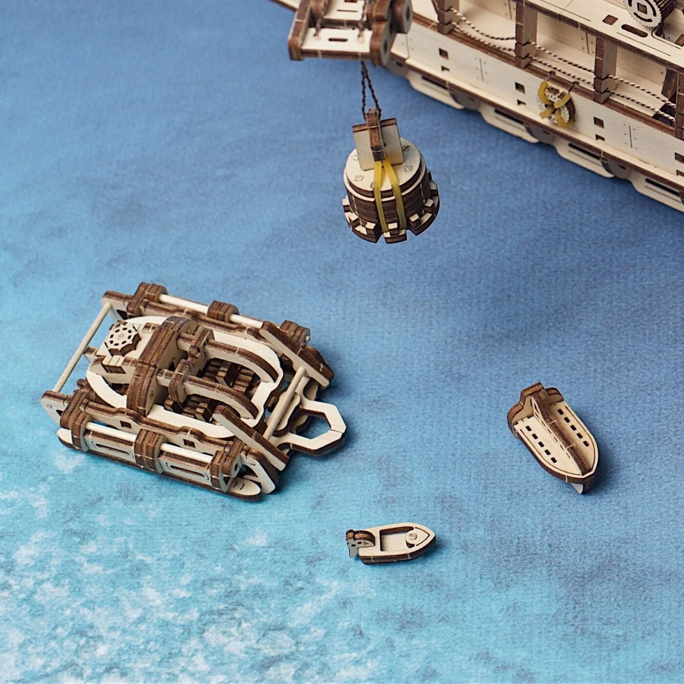 La grue hisse le bathyscaphe, à côté du petit bateau à moteur et du canot de sauvetage, sur fond bleu mer