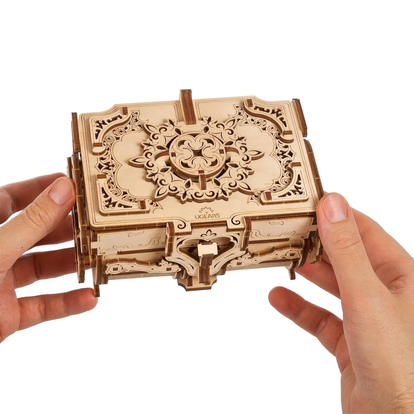 Deux mains tiennent le coffret antique fermé face à l'objectif