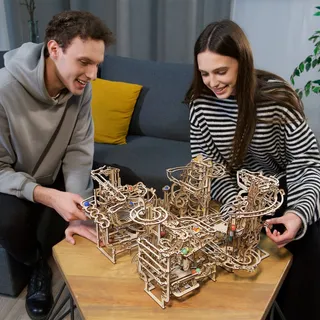 Un couple devant quatre circuits à billes Ugears reliés entre eux sur une table basse