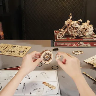 Mains assemblant une roue dentée au-dessus de la notice, la boîte du kit derrière