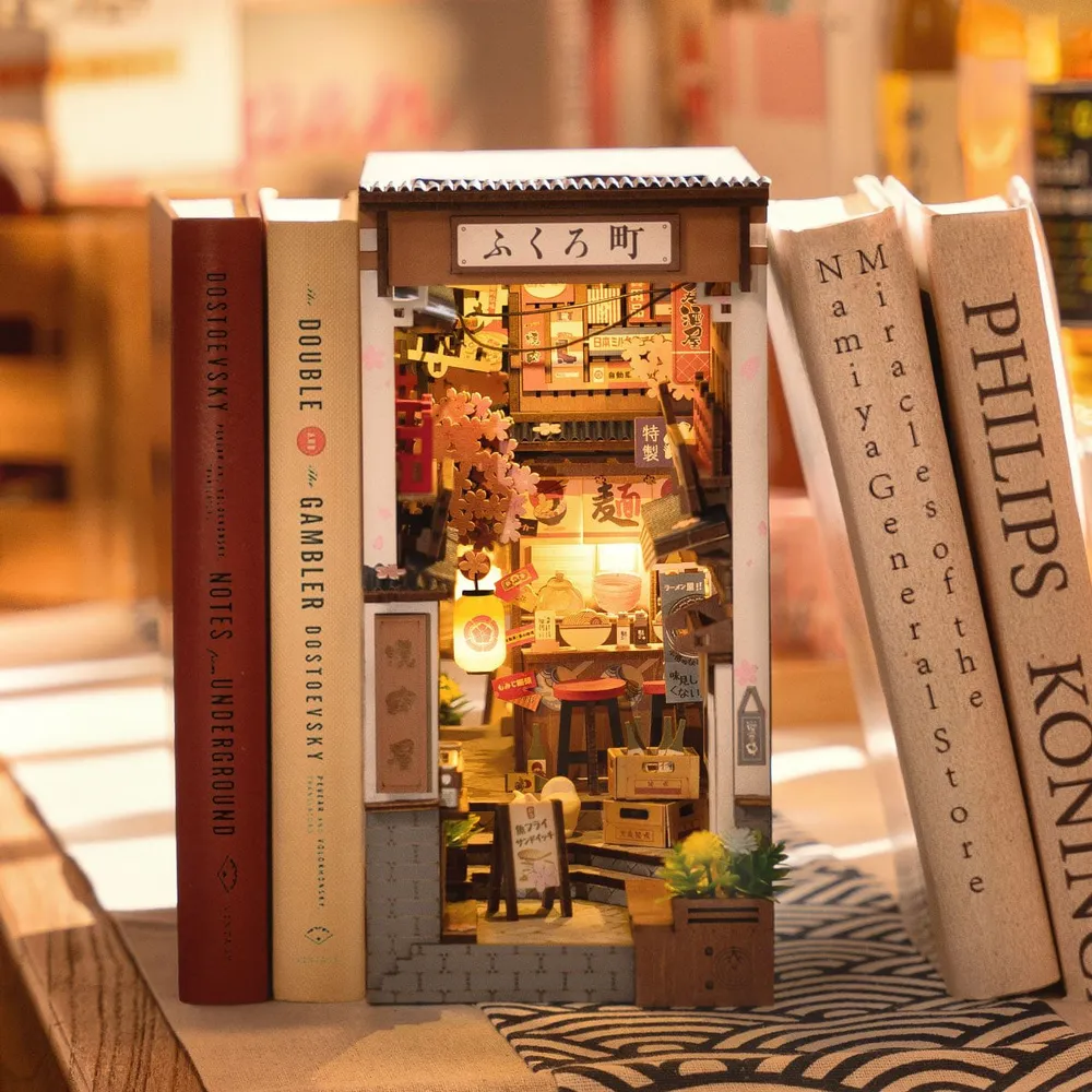 Le book nook calé entre de gros livres sur une table