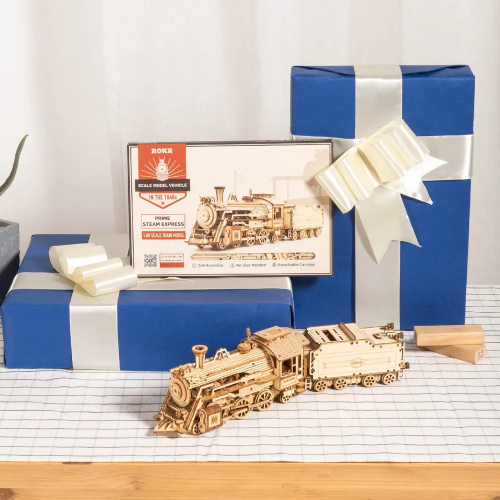 Locomotive en bois sur une nappe à carreaux entre des paquets cadeaux bleus enrubannés