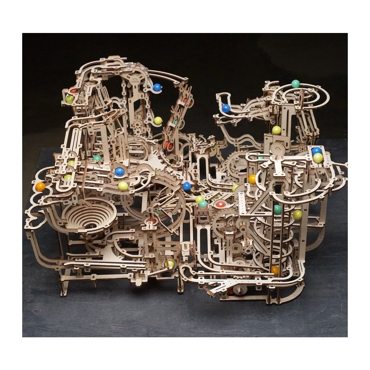 Les quatre circuits à billes de la gamme Ugears reliés en un seul parcours, sur fond sombre